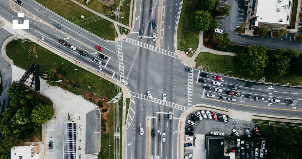 Aerial view of cars traveling through a multi-lane intersection with marked crosswalks and traffic signals